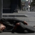 A City Worker Sprays Disinfectant As A Man Sleeps On The Street, In Central Mexico City