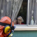 A Woman Waves To A City Worker Dressed In A Hazmat Suit As He Disinfects The Streets In Her Neighborhood As A Precaution Against The Spread Of The New Coronavirus, In Santiago, Chile