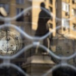 Apartment Blocks Are Reflected In The Window Of A Vintage Clock Repair Shop In Bucharest, Romania