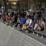 People Sit As Others Exercising In A Seafront Promenade In This Photo Taken With A Telephoto Lens In Barcelona, Spain