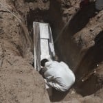 Worker Wearing Protection Suit Buries A Coffin In Ciudad Juarez Mexico