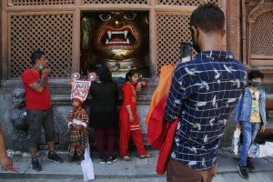 A Nepalese Girl Stands For A Photograph In Front Of An Idol Of Swet Bhairav Statue