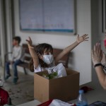 A Primary School Student Reacts Sending Kisses And A Hug From A Distance To Her Teacher, As She Collects Her Personal Belongings, During The Closing Of The School Year In A School In Barcelona, Spain