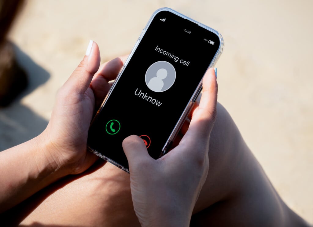Incoming Call With Unknown Caller, Malicious Phone Calls Concept. Unknown Number Displayed Showing On Smart Mobile Phone In Woman Hand On Leave Day At The Beach. Spam And Robocalls, Scam Call Alert.