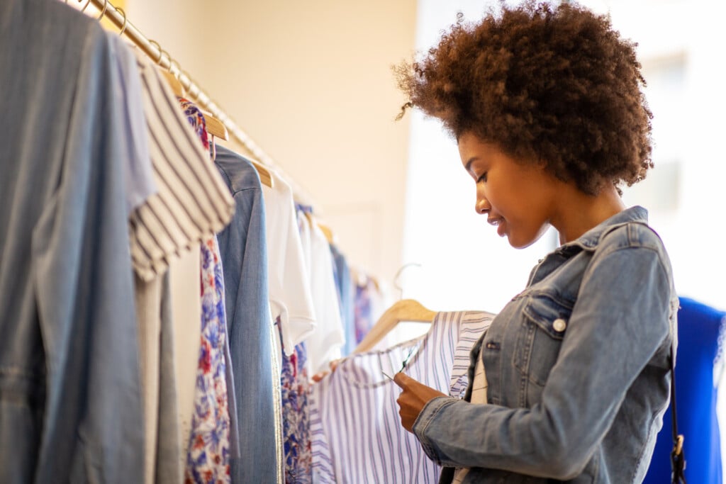 Side Of Beautiful Young Black Woman With Afro Shopping For Clothes In Store