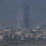 Smoke rises behind destroyed buildings by Israeli bombardments as seen inside the Gaza Strip from southern Israel, Thursday, Jan. 16, 2025. (AP Photo/Tsafrir Abayov)