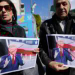 Palestinians carry defaced pictures of U.S. President Donald Trump while protesting against his latest statements regarding the transfer of Palestinians from Gaza, in the West Bank city of Ramallah Wednesday, Jan. 29, 2025. (AP Photo/Nasser Nasser)