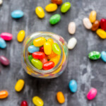 Glass Of Colourful Sweet Jellybeans On Gray Background