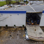 In an aerial view, a smashed truck sits under a section of collapsed warehouse wall after violent storms and tornadoes tore through the area on Thursday, April 3, 2025, in Jeffersontown, Ky. (AP Photo/Jon Cherry)