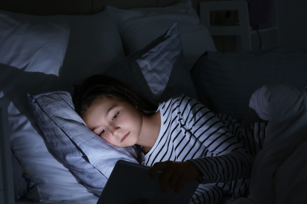 Little Girl Suffering From Sleep Disorder With Tablet Computer In Bedroom
