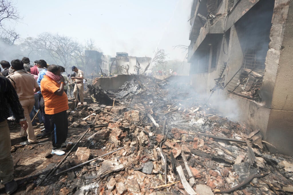 People stand around debris at the site of an airplane that crashed in India's northwestern city of Ahmedabad in Gujarat state, Thursday, June12, 2025. (AP Photo/Ajit Solanki)