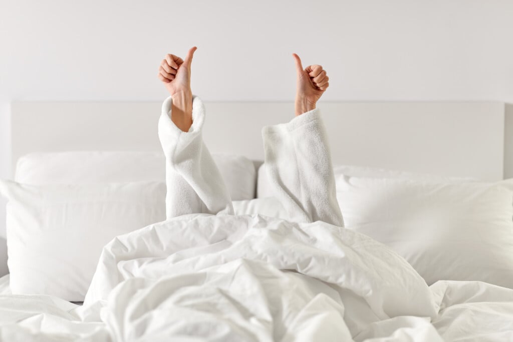 Hands Of Woman Lying In Bed And Showing Thumbs Up