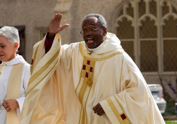 Episcopal Church Presiding Bishop-elect Michael Curry gives waves to the crowd as he arrives at the Washington National Cathedral