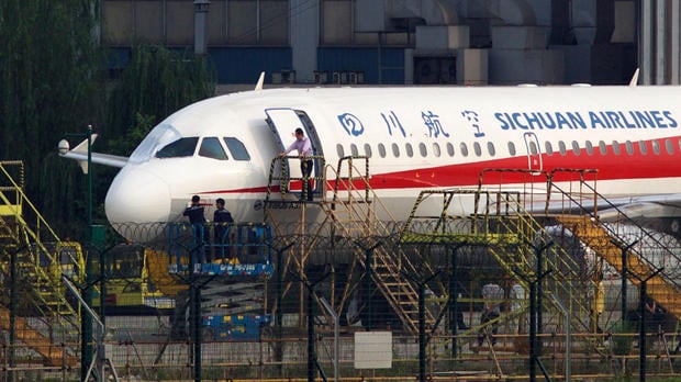 Workers inspect a Sichuan Airlines aircraft that made an emergency landing after a windshield on the cockpit broke off