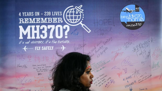 A woman walks past a banner bearing solidarity messages for passengers of the missing Malaysia Airlines flight MH370