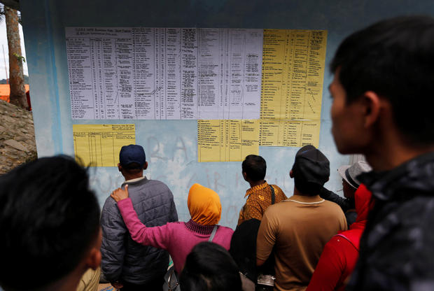 Villagers and relatives look at a list of missing passengers from Monday's ferry accident at Lake Toba in Simalungun