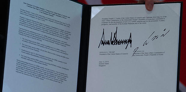 US President Donald Trump holds up a document signed by him and North Korea's leader Kim Jong Un following a signing ceremony during their historic US-North Korea summit
