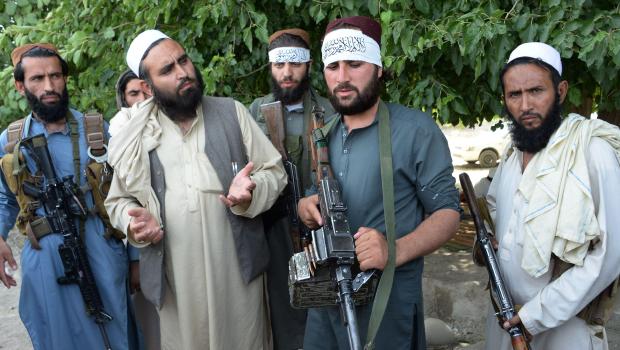 Afghan Taliban militants stand with residents as they took to the street to celebrate ceasefire on the second day of Eid in the outskirts of Jalalabad on June 16
