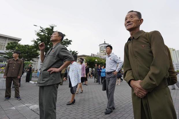 North Korean watch news report on North Korea's leader Kim Jong Un's Singapore visit in front of an electronic screen at Pyongyang station in Pyongyang