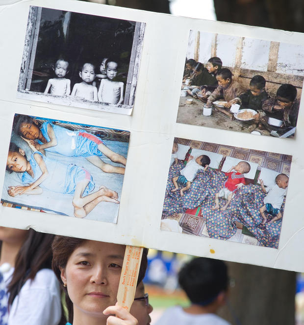 A woman holds up a poster with photos from an internment camp in North Korea during a White House vigil at Lafayette Park July 10