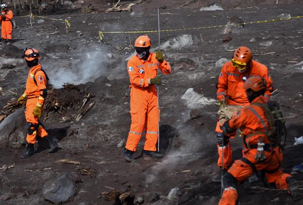 Volunteer firefighters search for victims of Sunday's Fuego Volcano eruption in Alotenango