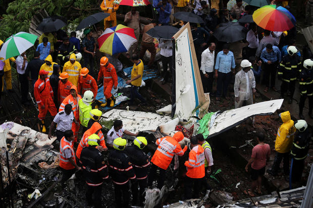 Firefighters and aircraft rescue workers inspect the site of a plane crash in Mumbai 