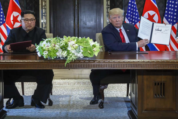 U.S. President Donald Trump holds up the document that he and North Korea leader Kim Jong Un just signed at the Capella resort on Sentosa Island Tuesday