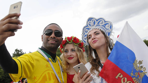 A Brazil fan takes a selfie picture with Russian supporters in a fan zone near the main building of the Moscow State University in Moscow on June 14