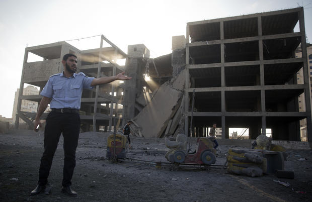A Palestinian policeman guards next to a destroyed building following an Israeli airstrike in Gaza City