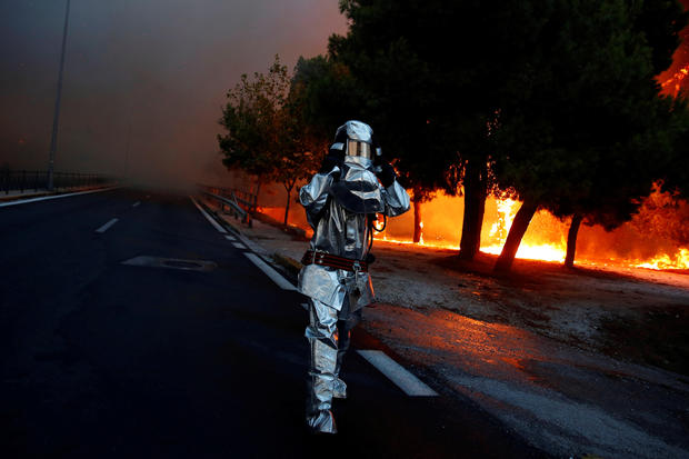 A firefighter wears a flame resistant uniform as wildfire burns in the town of Rafina
