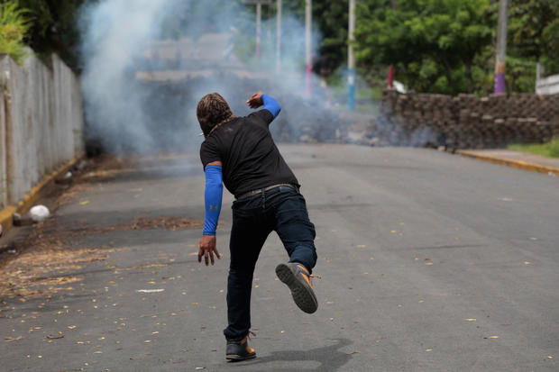 A demonstrator throws a homemade device during the funeral service of Jose Esteban Sevilla Medina