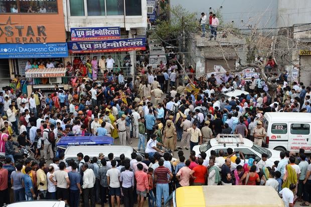 Onlookers gather along a road near the site where 11 family members were found dead inside their home in the neighbourhood of Burari in New Delhi on July 1