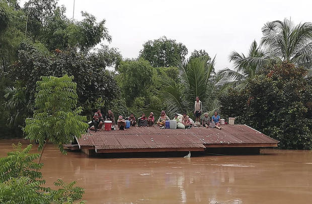 Villagers take refuge on a rooftop above flood waters from a collapsed dam in the Attapeu district of southeastern Laos
