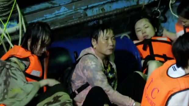 Rescued people in life jackets sit on a fishing boat after a boat they were travelling in capsized off the tourist island of Phuket 