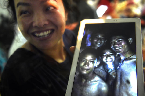 A happy family member shows the latest picture of the missing boys taken by rescue divers inside Tham Luang cave  when all members of children's football team and their coach were found alive in the cave at Khun Nam Nang Non Forest Park in the Mae Sai district of Chiang Rai province late July 2