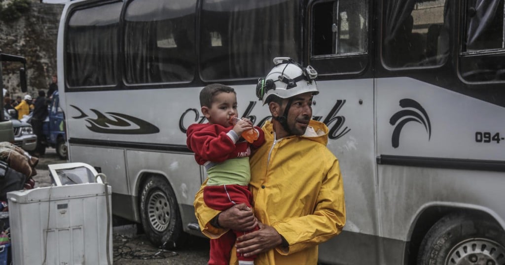 dpatop - A member of the Syrian Civil Defence (White Helmets) carries a child