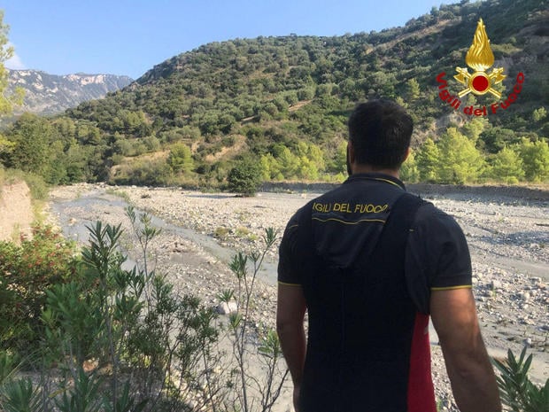 A firefighter stands in the area after several people were killed in a mountain gorge flooding, in the municipality of Civita 