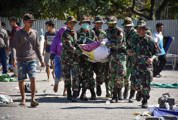 Indonesian soldiers carry the body of an earthquake victim to an ambulance at North Lombok District General Hospital in Tanjung 