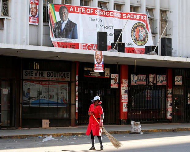A woman sweeps the street outside the opposition Movement for Democratic Change (MDC) headquarters in Harare 
