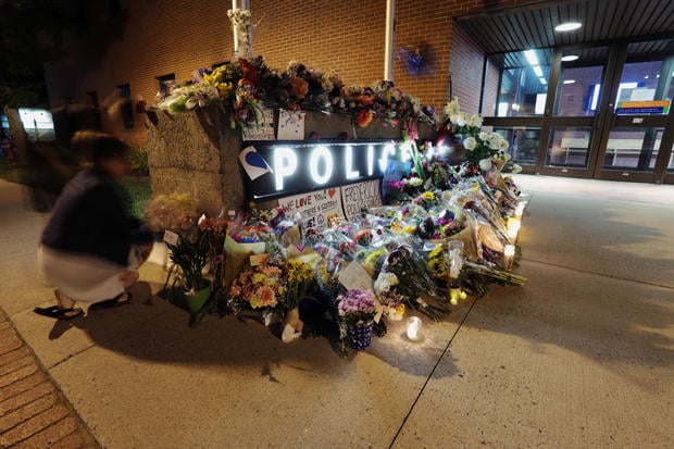 Fredericton residents pay their respects at a makeshift shrine created in front of police headquarters after four people