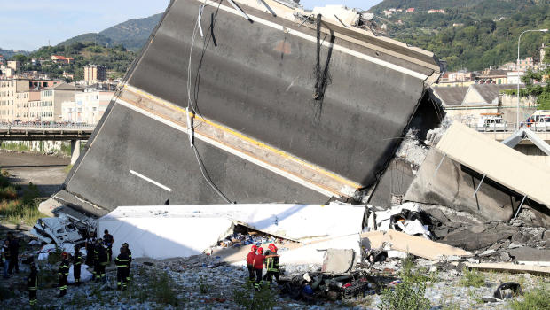 Firefighters and rescue workers stand next to a part of the motorway