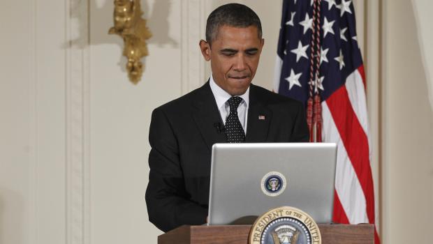 President Barack Obama uses a laptop computer to send a tweet during a "Twitter Town Hall" in the East Room of the White House in Washington