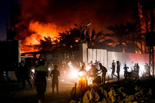 Iraqi protesters gather outside the burning headquarters of the Iranian consulate in the southern city of Basra on September 7