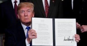 U.S. President Donald Trump holds his signed memorandum on intellectual property tariffs on high-tech goods from China