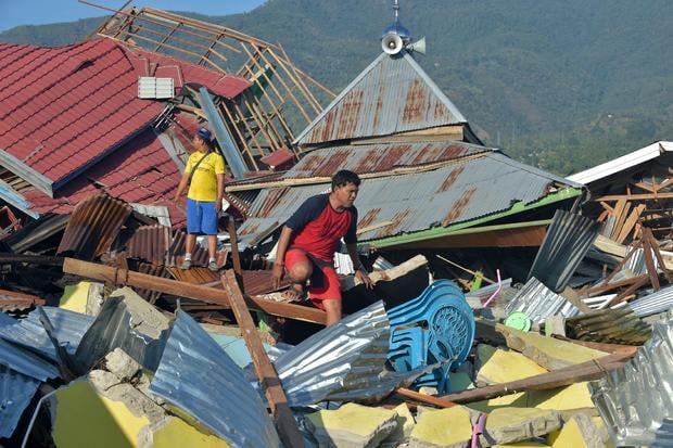 People inspect damaged houses in Palu