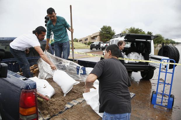 Business owners fill up sand bags from the back of a truck as they try to protect businesses during a flash flood as a result of heavy rains from tropical storm Rosa Tuesday