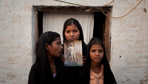 FILE PHOTO: The daughters of Pakistani Christian woman Asia Bibi pose with an image of their mother while standing outside their residence in Sheikhupura located in Pakistan's Punjab Province November 13