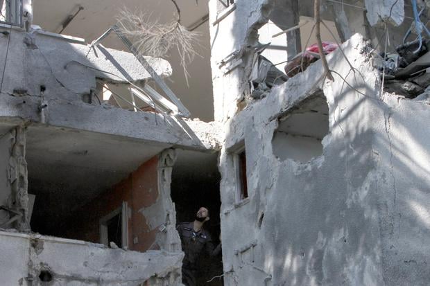 An Israeli policeman inspects the damage in a building caused a day earlier by a rocket fired from the Gaza Strip