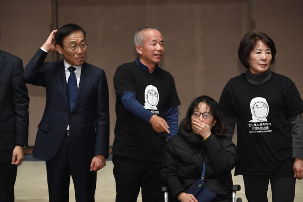 Samsung Electronics co-president Kim Ki-nam (L) poses for a photo with relatives of victims of work-related diseases of its semiconductor and LCD factories after he made a formal apology in Seoul on November 23