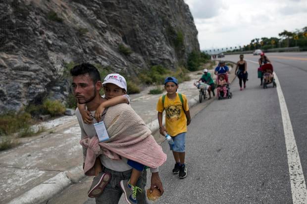Honduran migrant Jose Macy carries his four-year-old nephew Yair Perez as the thousands-strong caravan of Central Americans migrants hoping to reach the U.S. border moves onward from Juchitan